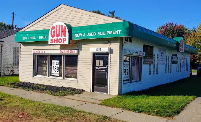All Listings 1 A beige building with a green awning labeled "Gun Shop" offers buying, selling, and trading services for new and used equipment. Signs advertise cash for gold and cash for guns. The storefront has large windows and a door with a sign on it.