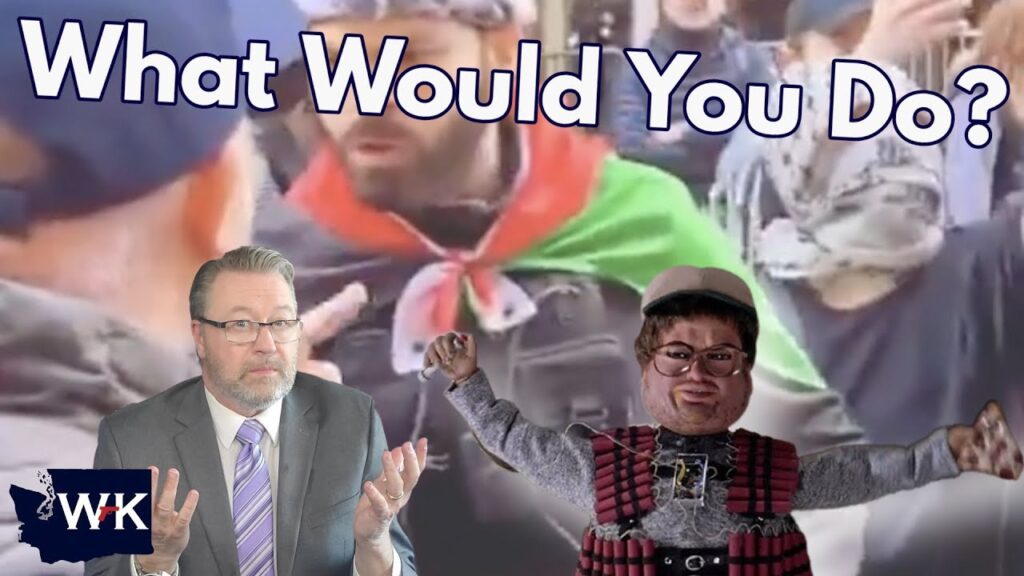 A man in a suit shrugs in the lower left corner, while a protest scene with people in headscarves and a flag appears behind bold text reading "What Would You Do?" A puppet in a plaid outfit stands in the center.