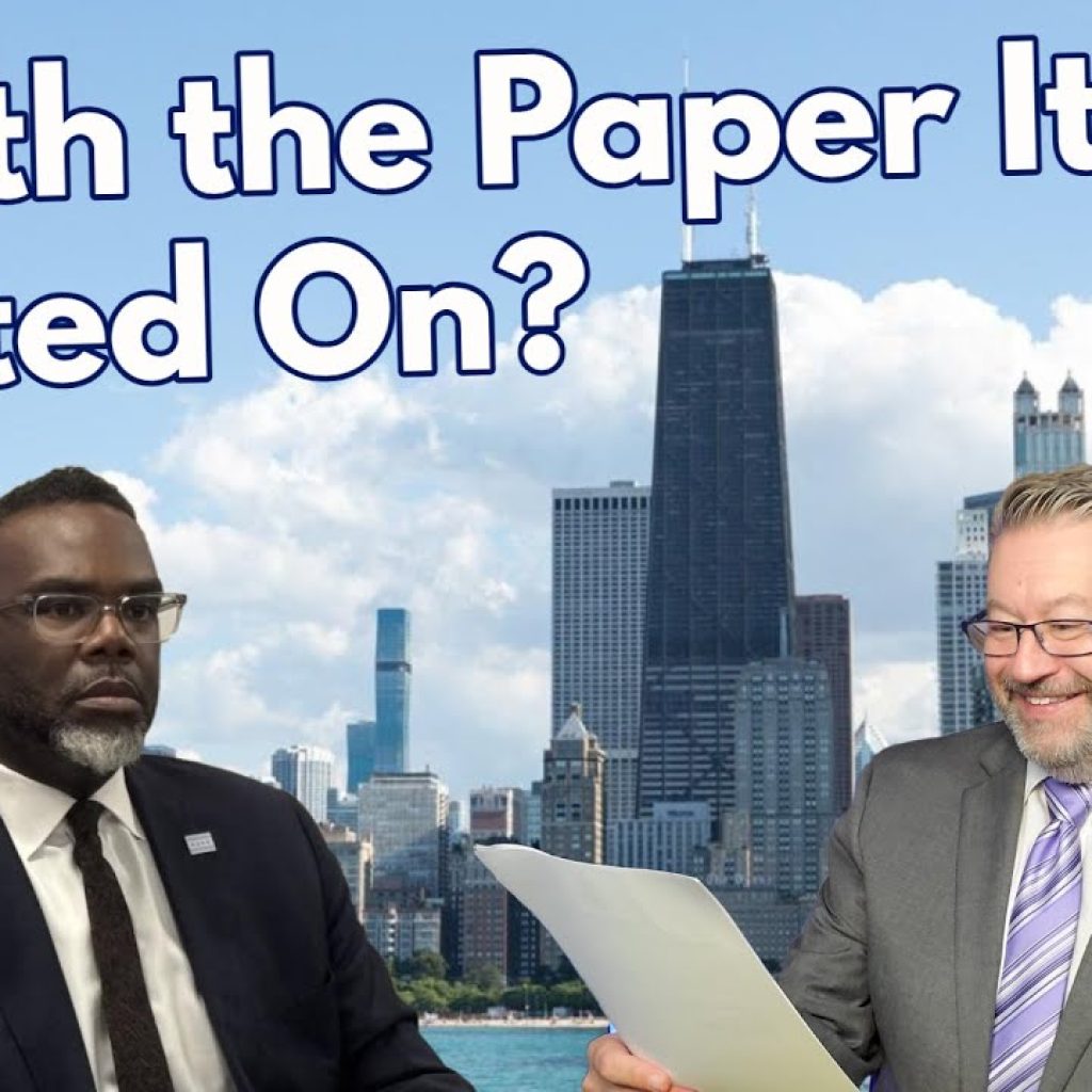 Two men in suits sit in front of a backdrop featuring a city skyline. Large text above them reads, "Worth the Paper It’s Printed On?" One man looks serious while the other smiles and holds a document.
