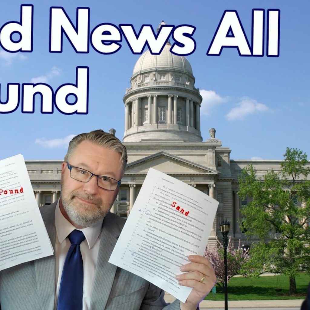 A man in a suit holds up two documents labeled "Pound" and "Sand" in front of a government building, with the text "Good News All Around" above. Part of another man's face is visible on the right. The WK logo is in the corner.
